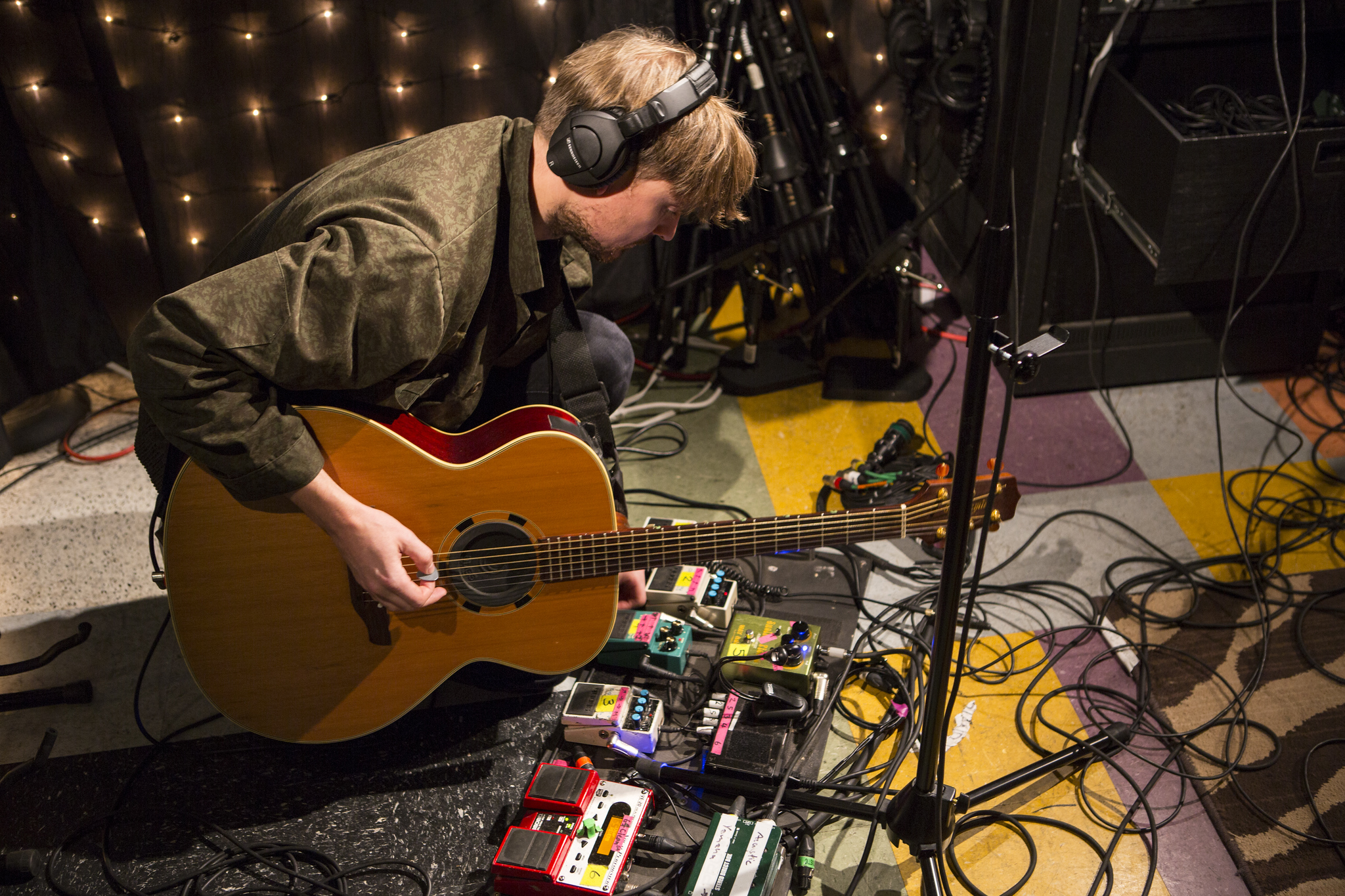 student playing a guitar and looking at various guitar pedals