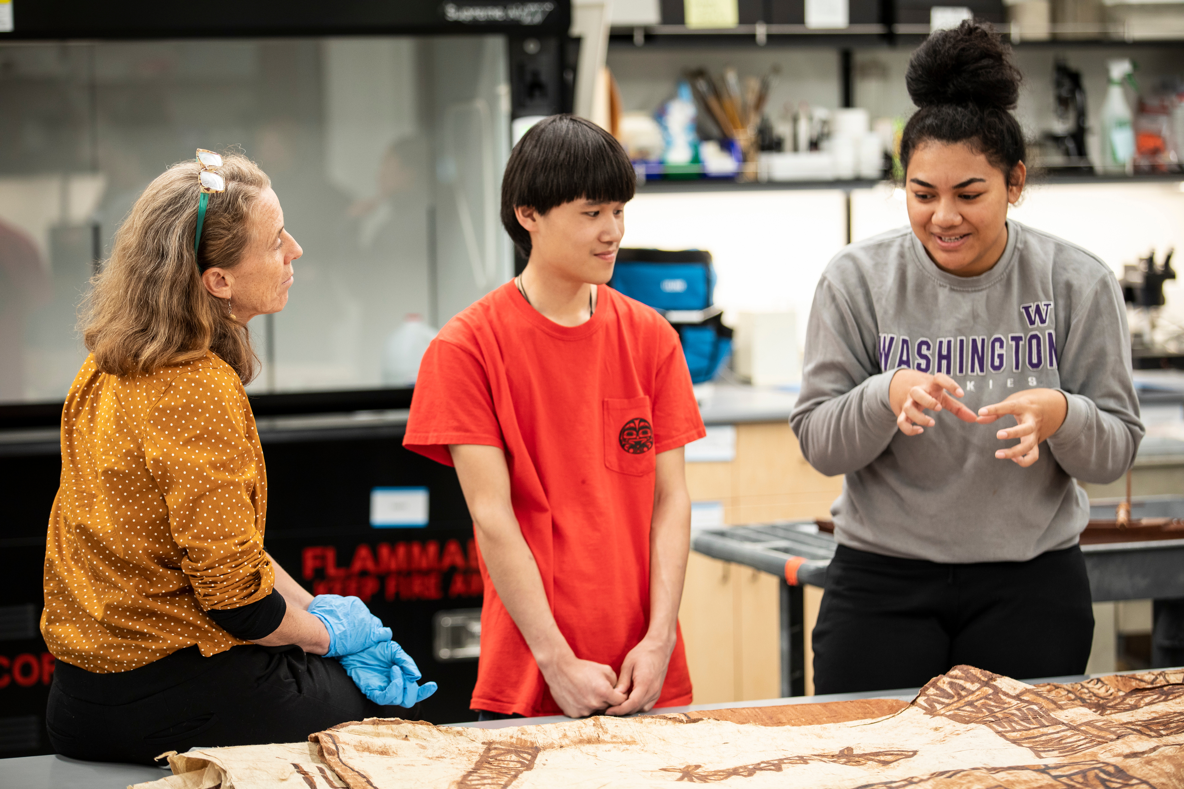 Holly Barker meeting with two students inside the Burke Museum
