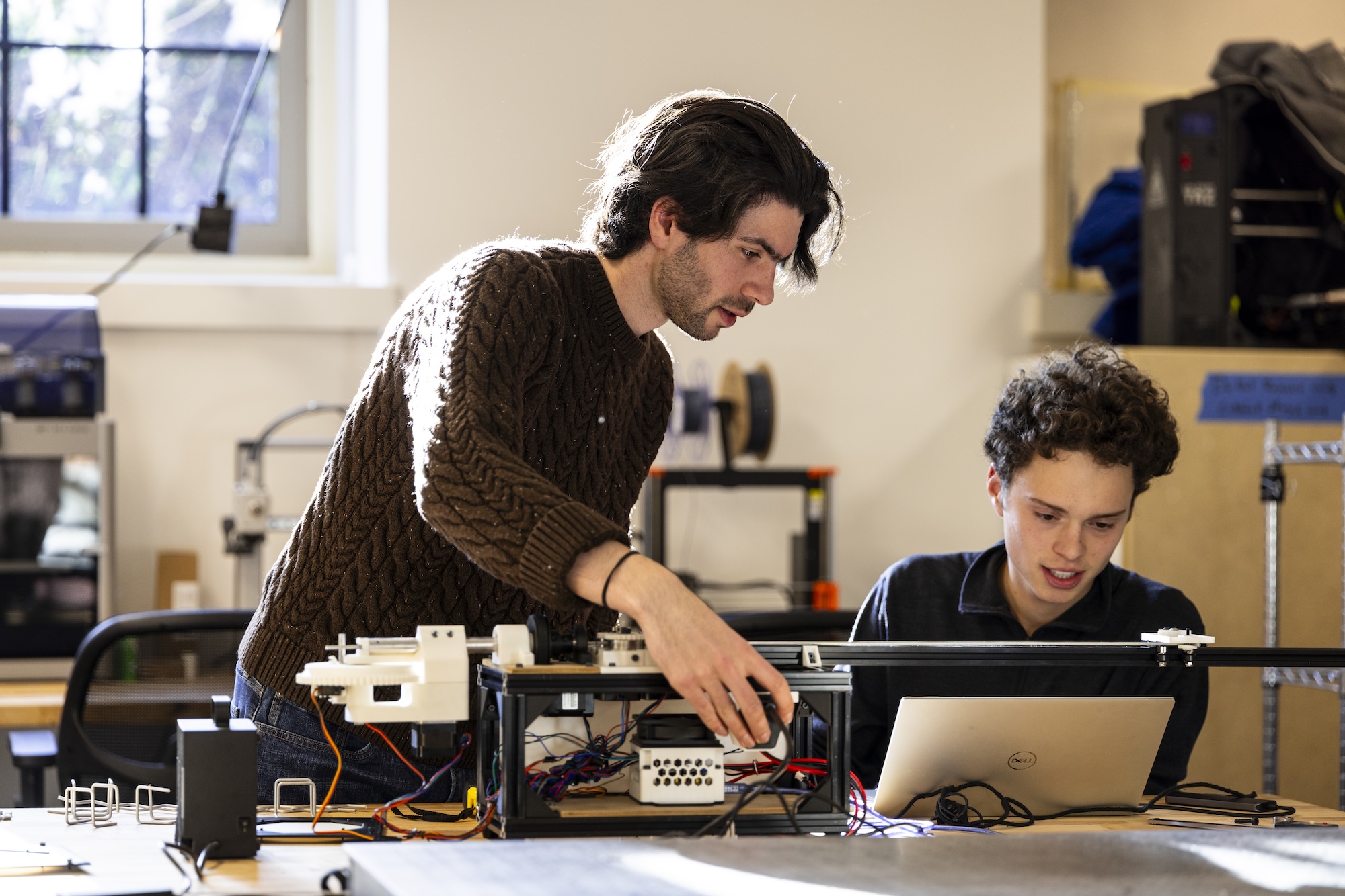Two students looking at equipment and an open laptop in a math lab