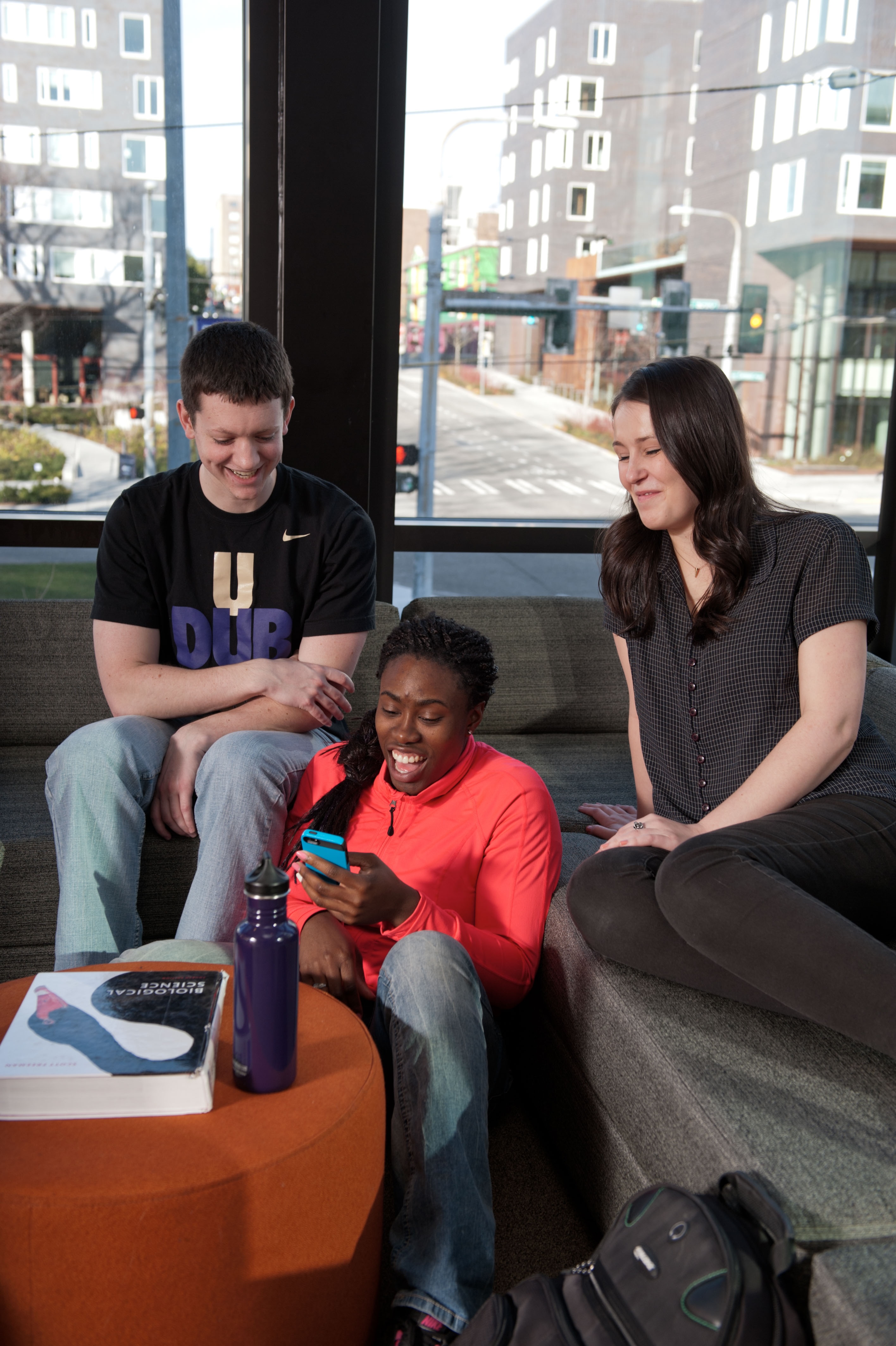 Three students looking at a phone together in a residential hall.